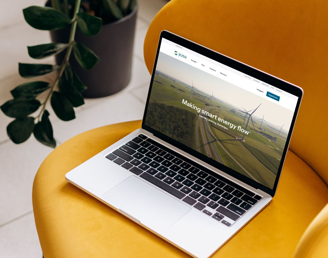 Laptop op een gele zetel met de homepage van Yuso: making smart energy flow.